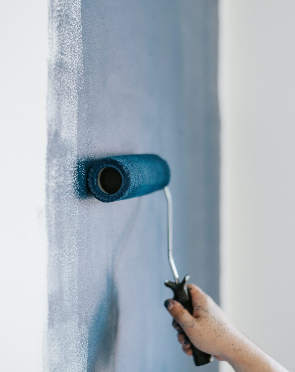 A closeup shot of a female using paint rollers with the color blue
